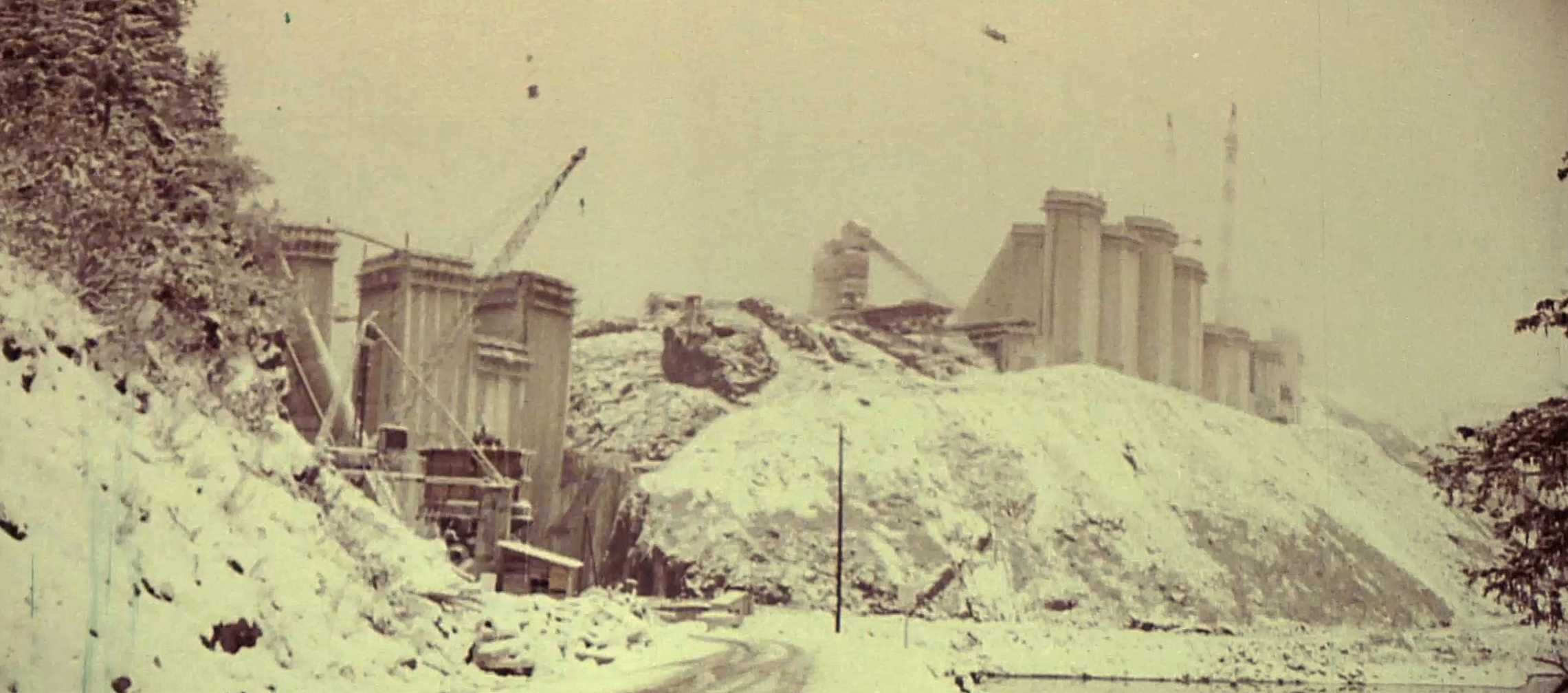 Panoramique côté amont de la construction de la voûte et des contreforts durant des chutes de neige